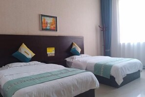 A hotel room with two beds, a headboard, a framed picture, and a window with curtains. - Hurui Hotel (Mile)