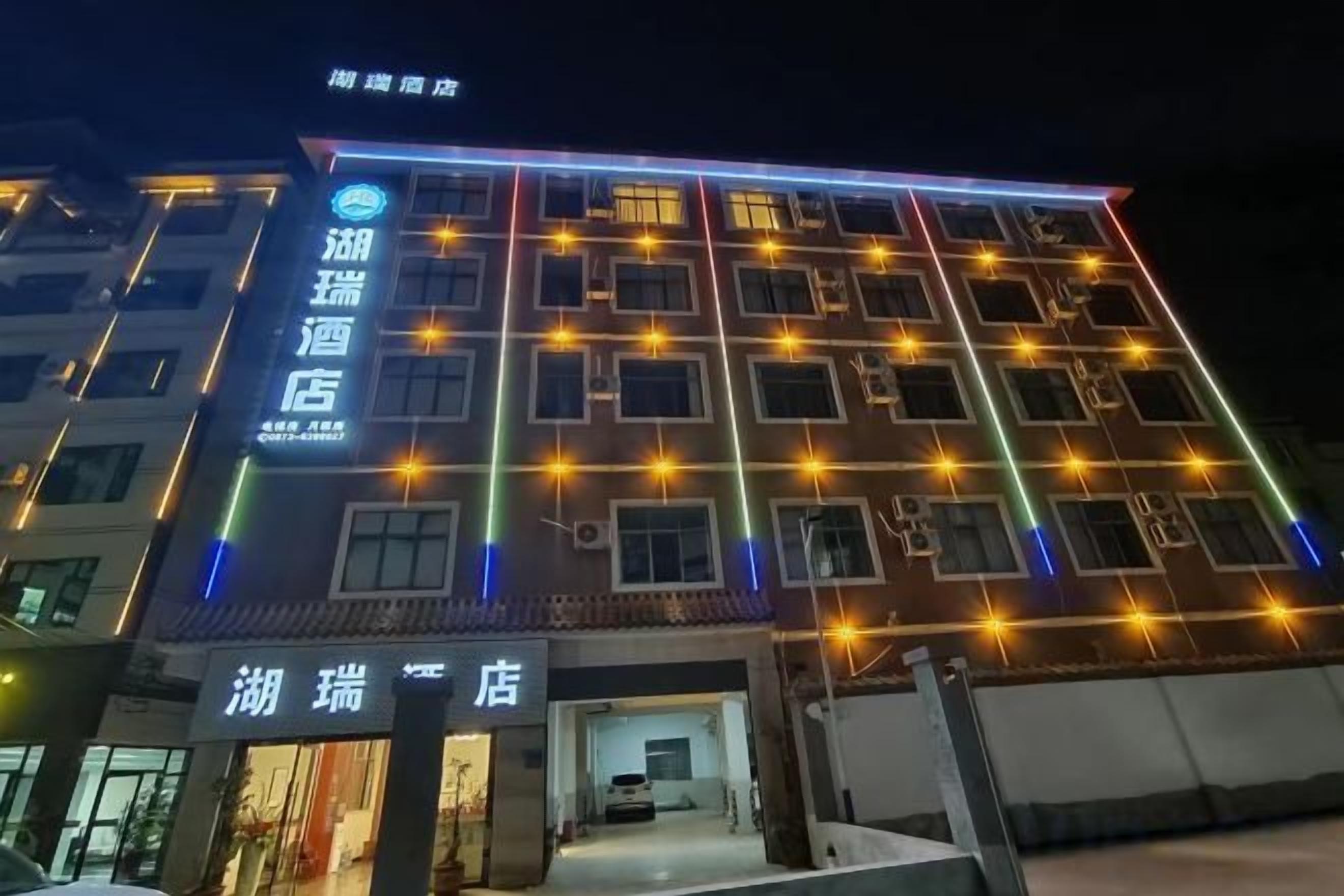 Um hotel com vários andares, sinalização iluminada e entrada visível.