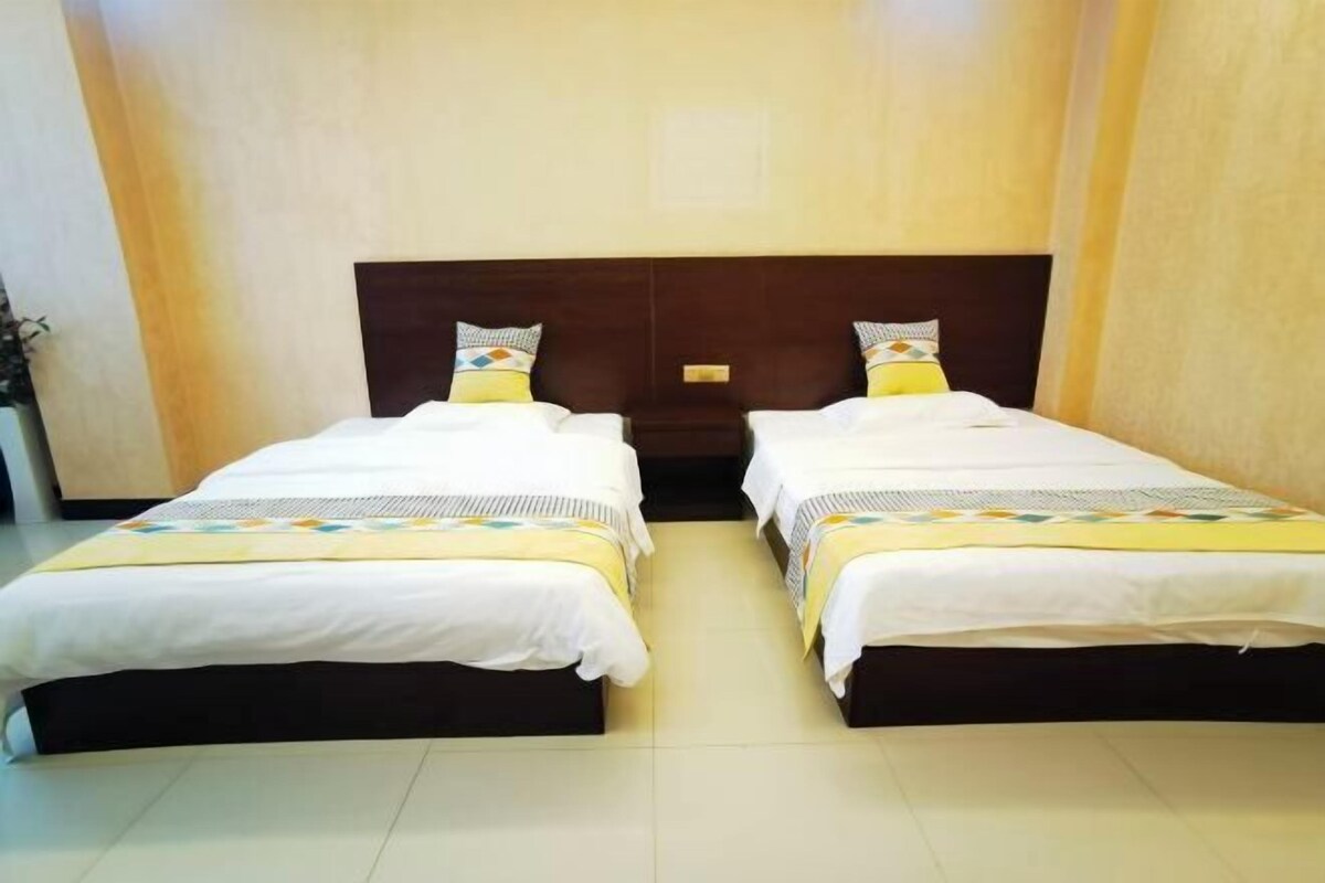A hotel room with two beds, each with a wooden headboard and white bedding.