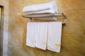 A bathroom with a towel rack holding three white towels and a folded towel on top. - Hurui Hotel (Mile)