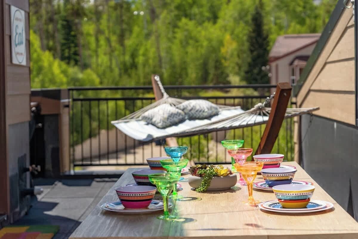 A balcony with a hammock, colorful bowls, and a potted plant.