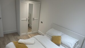 A bedroom with a bed, white pillows, a yellow throw blanket, and a white wardrobe. - 3Br-Free Parking- Near Transport Links (London)