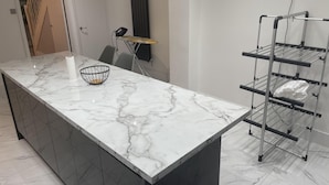 A modern kitchen with a marble countertop, a black wire basket, and a metal drying rack. - 3Br-Free Parking- Near Transport Links (London)