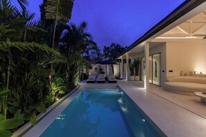 A modern pool area with lounge chairs and a glass-enclosed seating area. - Calamus - Tropical Minimalistic Villa in Bali (Bali)