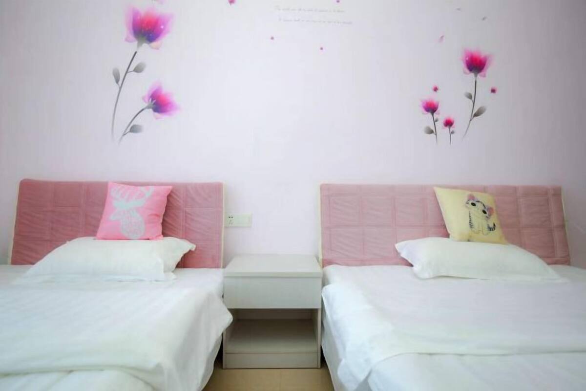 A twin room with two beds, each with a pink headboard and white bedding.