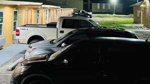 A parking area with a white pickup truck and a black SUV. - EXPRESS INN & SUITES (El Campo)