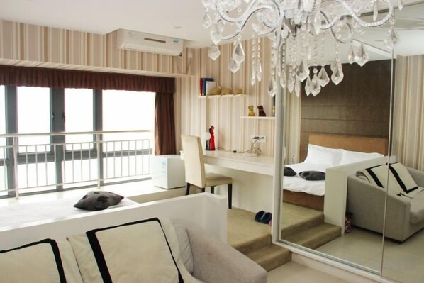 Una habitación de hotel moderna con balcón, escritorio, cama y zona de estar.
