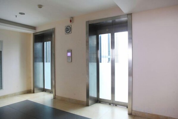 An elevator area with two elevators, a wall-mounted emergency phone, and a floor mat. - Han Palace Ginza Apartment (Wuhan)