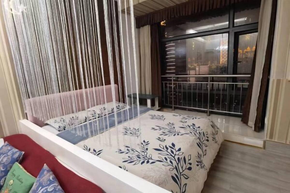 A bedroom with a bed, a window with a view, and a balcony.
