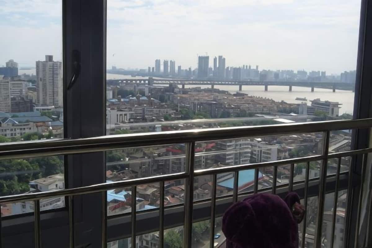 A view from a high-rise window overlooking a cityscape with a river, bridges, and buildings.