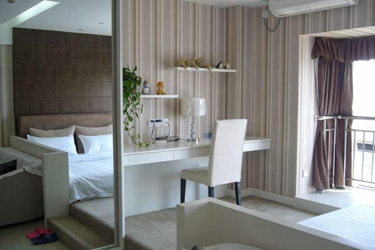 A hotel room with a bed, a desk, a chair, and a balcony.