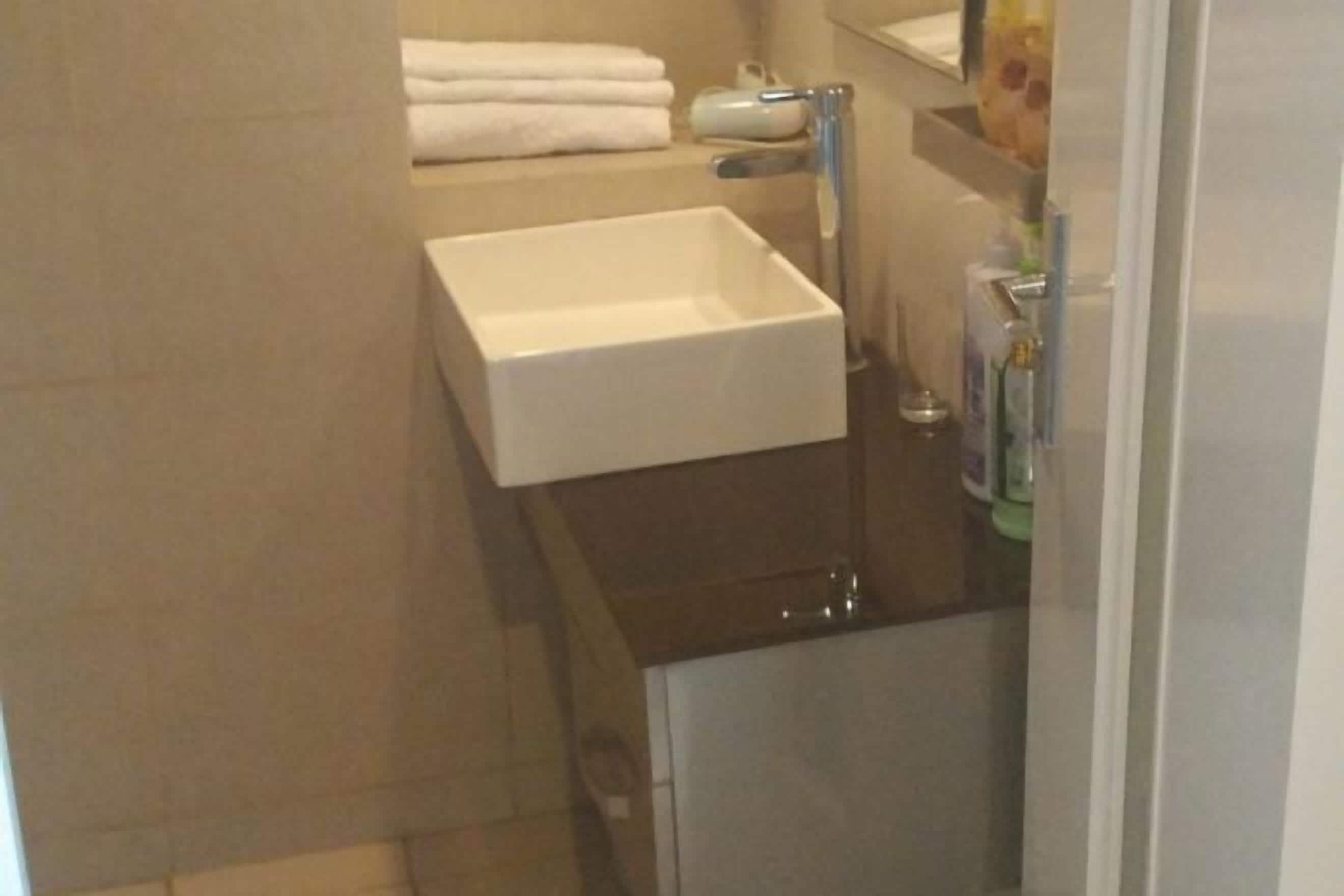 Une salle de bain avec un lavabo blanc, un porte-serviettes avec des serviettes pliées et un miroir au-dessus du lavabo.