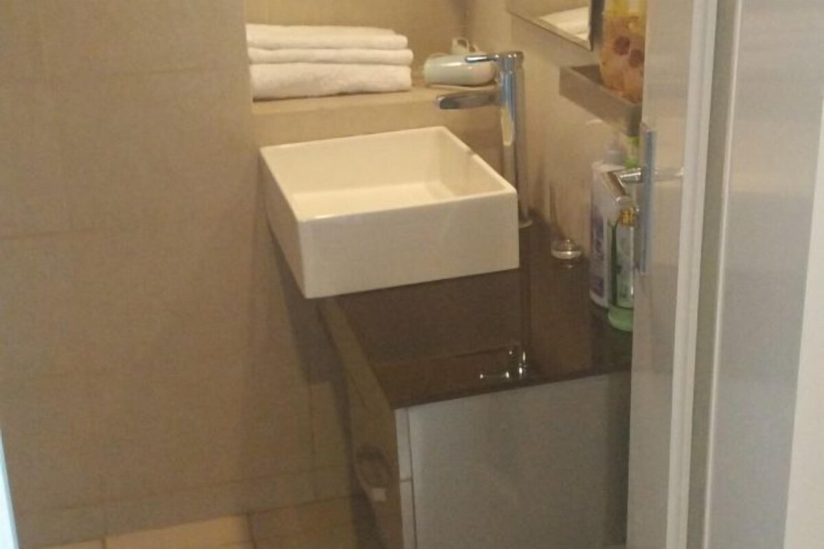 A bathroom with a white sink, a towel rack with folded towels, and a mirror above the sink.