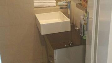 Une salle de bain avec un lavabo blanc, un porte-serviettes avec des serviettes pliées et un miroir au-dessus du lavabo.