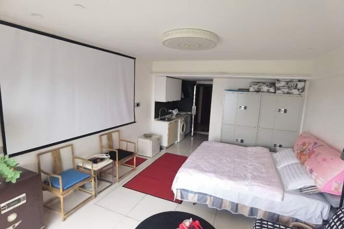 A bedroom with a bed, a desk, a chair, a TV, and a wardrobe.