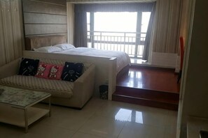 A hotel room with a bed, a sofa, a coffee table, and a window with curtains. - Han Palace Ginza Apartment (Wuhan)