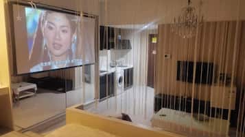 A hotel room with a large TV, a bed, and a view of the bathroom.