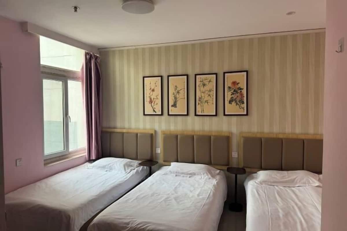 Ett hotellrum med två separata sängar, ett fönster med gardiner och fyra inramade konstverk på väggen.