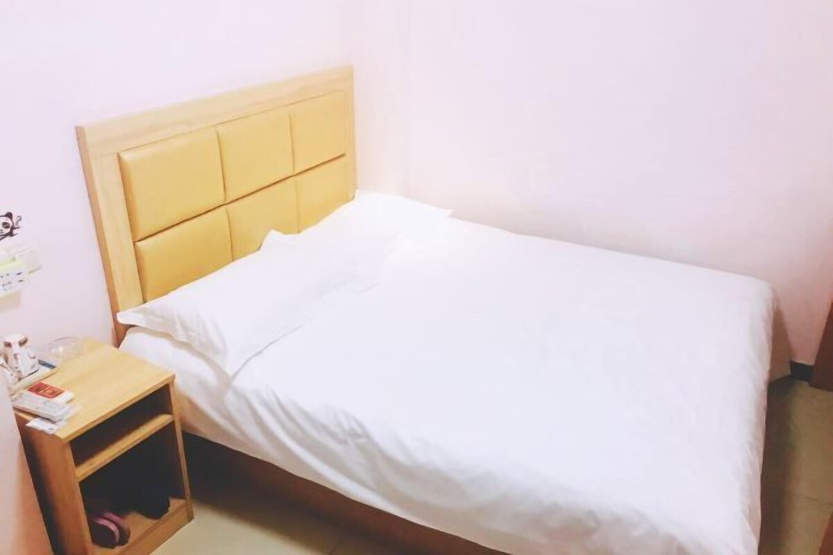 Ein Einzelbett mit Holz Kopfteil, einem Nachttisch und einer Ablage darunter.