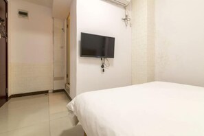 Ein Hotelzimmer mit Bett, Wandfernseher und Duschbereich.