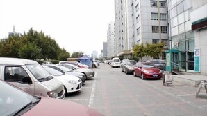 A parking lot with several cars parked along a street lined with tall buildings. - Tianjin Jiajun Express Hotel (Tianjin)