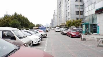 Un estacionamiento con varios coches aparcados en filas, junto a un edificio con un letrero.