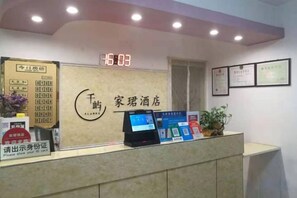A hotel reception desk with a digital display, framed certificates, and a clock. - Tianjin Jiajun Express Hotel (Tianjin)