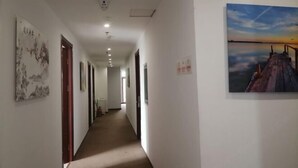A hallway with a painting of a sunset over water on the right wall. - Tianjin Jiajun Express Hotel (Tianjin)