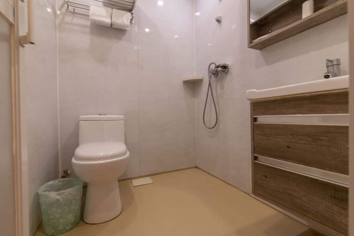 A small bathroom with a toilet, shower, and wooden vanity.