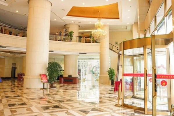 A hotel lobby with a check-in counter, a revolving door, and a chandelier. - Jinyu Longcheng Hotel (Zhijin)