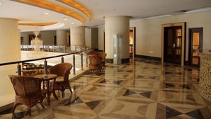 A spacious lobby with a geometric patterned floor, a chandelier, and wicker furniture.