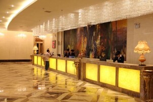 A hotel reception area with a long counter, a large mural on the wall, and a polished floor.
