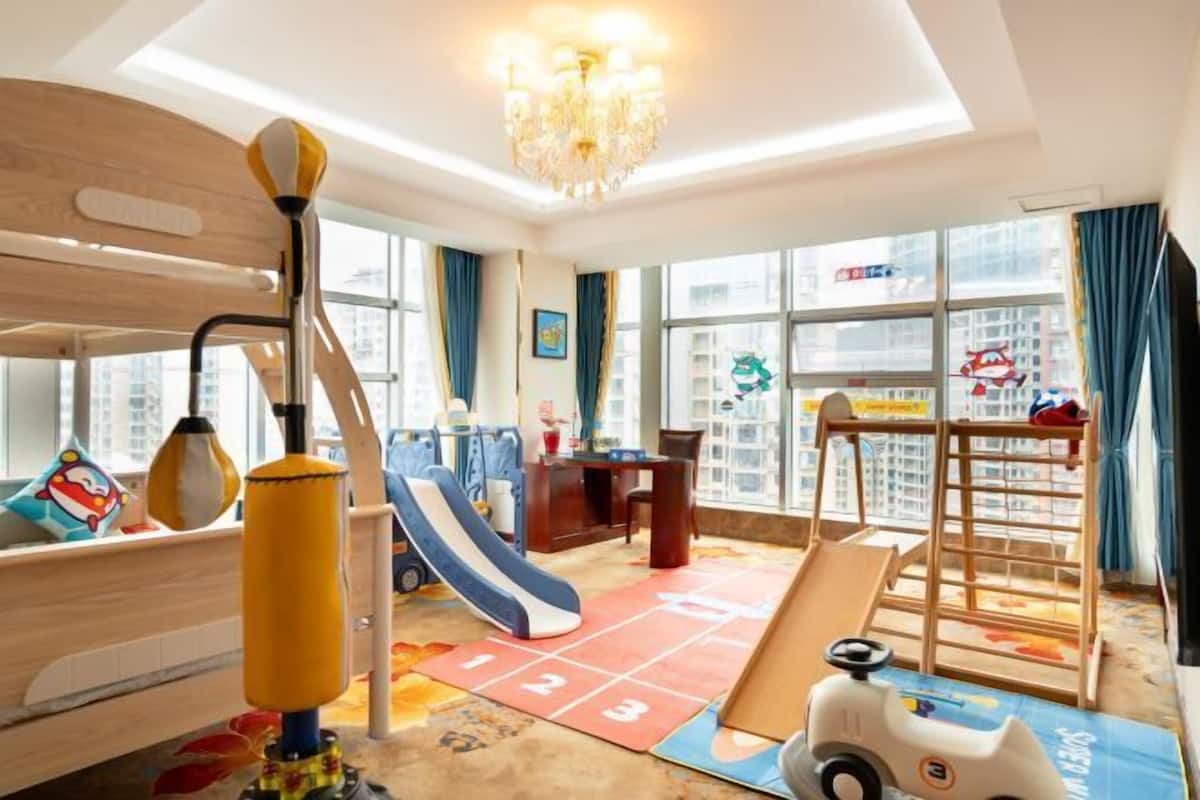 Sala de juegos infantiles con tobogán, pared de escalar y un coche de juguete.