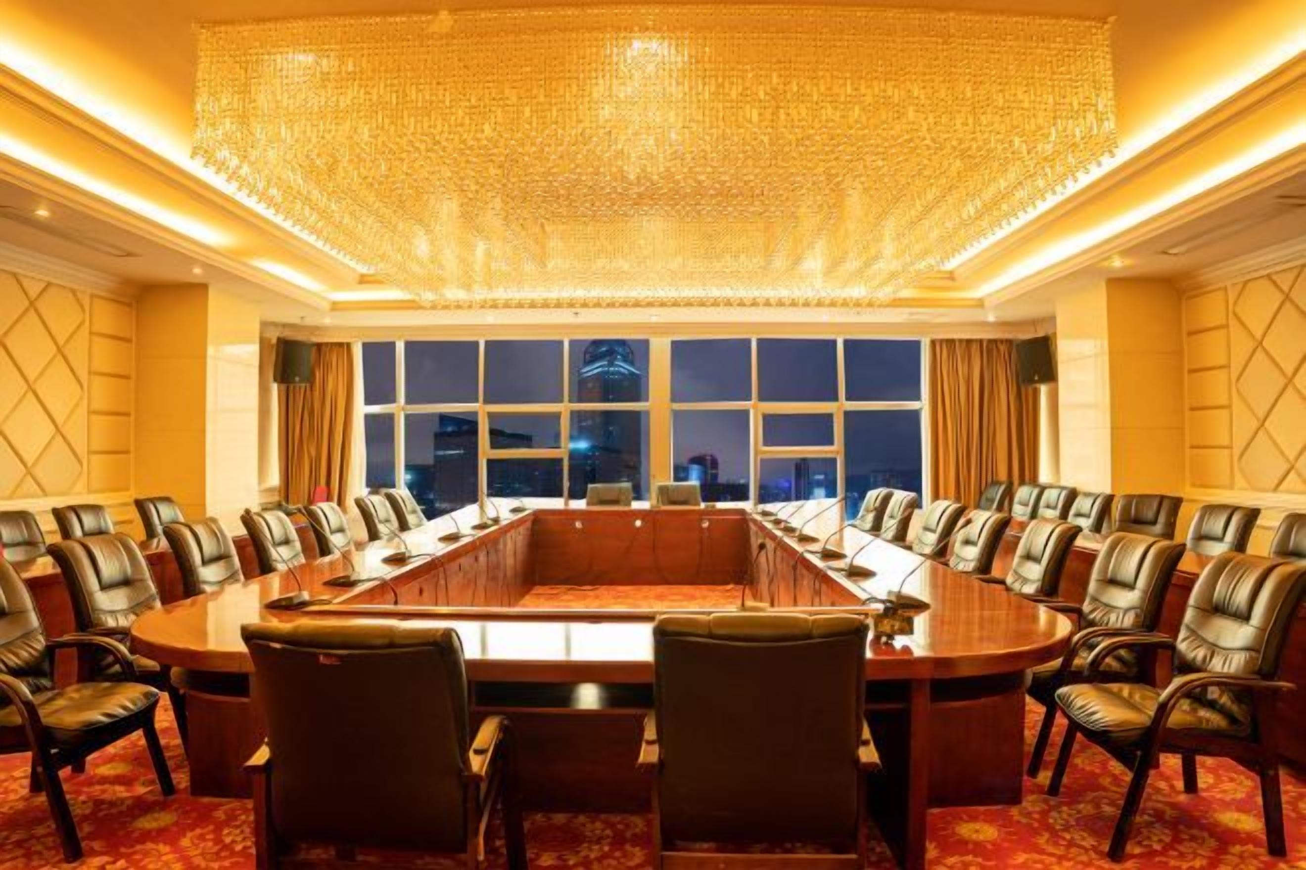 A conference room with a large oval table, leather chairs, and a view of the cityscape through large windows.