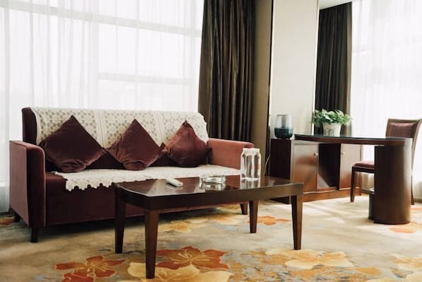 A living room with a sofa, coffee table, and a dining area with a table and chairs.