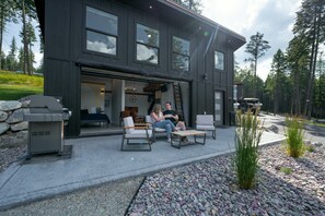 Un edificio moderno de dos pisos con un patio que incluye mobiliario exterior.