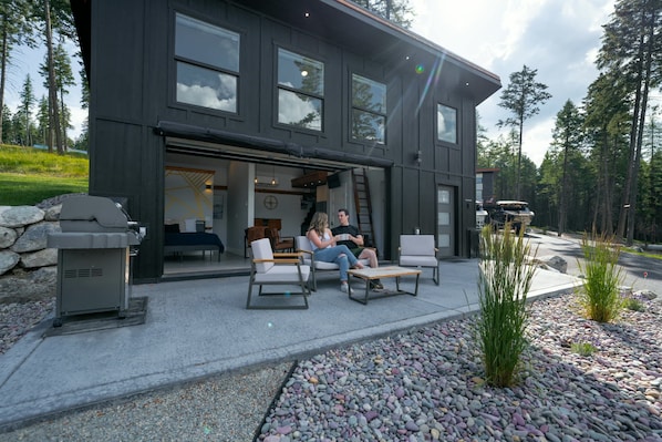A modern two-story building with a patio area featuring outdoor seating.