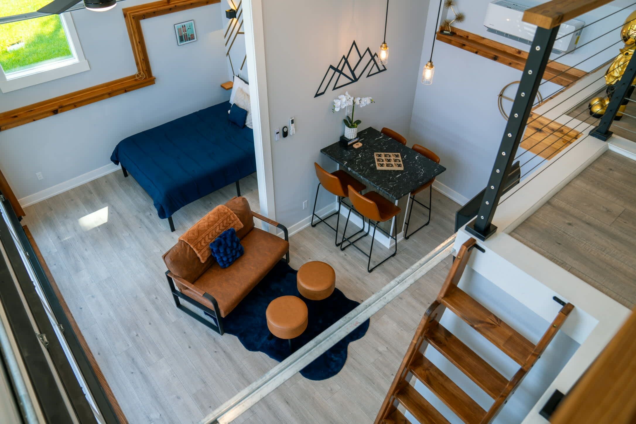 Un interior moderno con un sofá, otomanas, una mesa de comedor y una escalera.