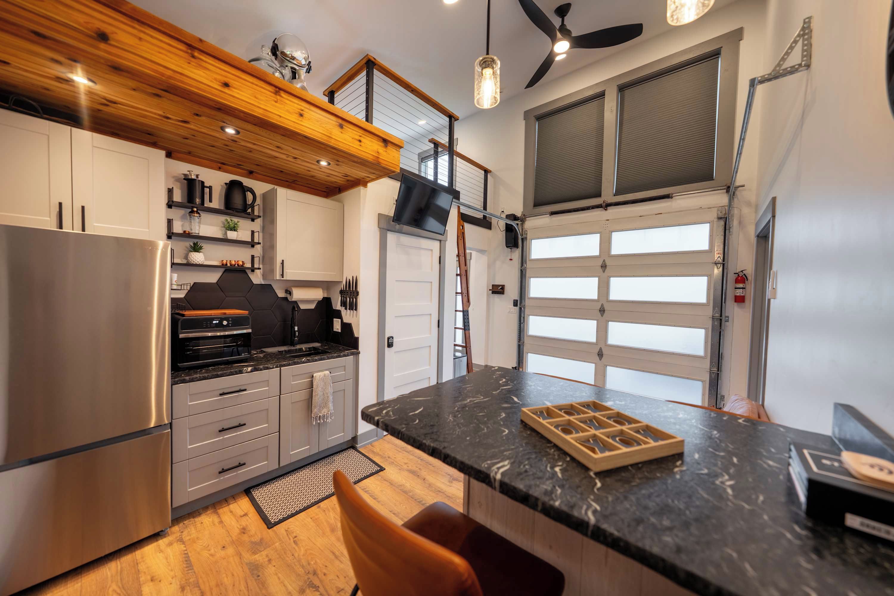 A modern kitchen with a central island, built-in appliances, and a ceiling fan.