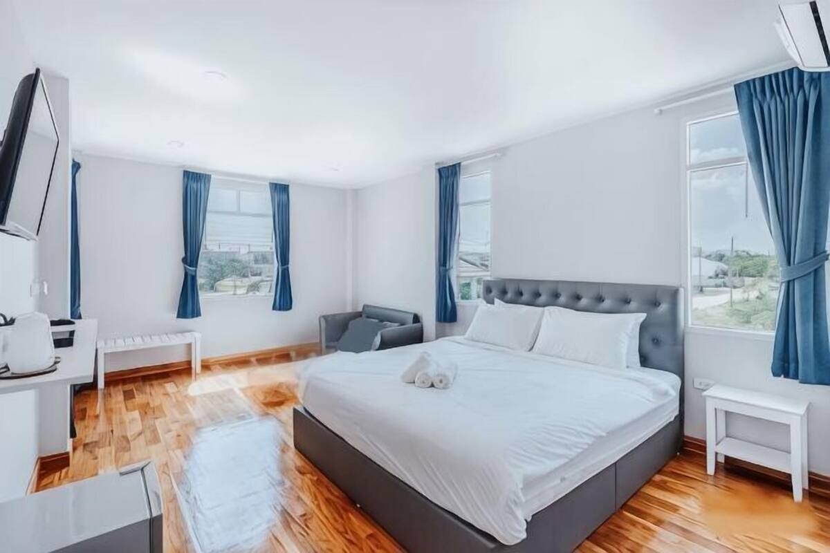 A modern hotel room with a large bed, a desk, a chair, and a view of the city.