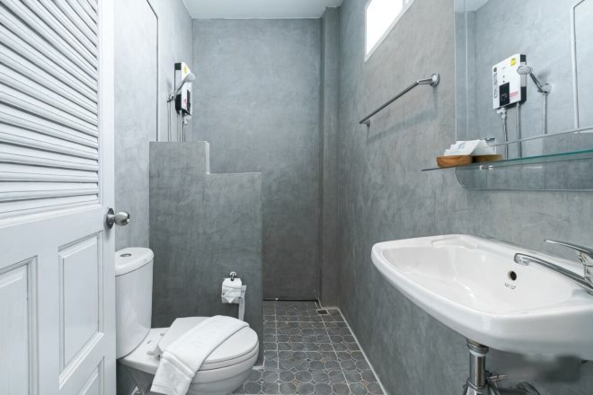 Un baño con inodoro, ducha y lavamanos, todo con un diseño moderno.
