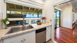 A modern kitchen with a large window, a dishwasher, and a wooden floor.