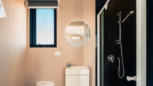 Un baño pequeño con inodoro, lavamanos y ducha.