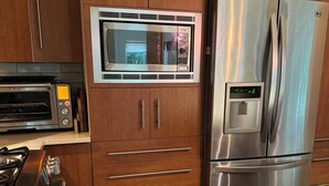 A modern kitchen with wooden cabinets, a stainless steel refrigerator, a built-in oven, and a gas stove.