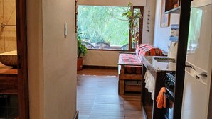 Keittiössä on puinen katto, ikkunasta avautuu näkymä vehreään maisemaan ja siellä on myös jääkaappi.