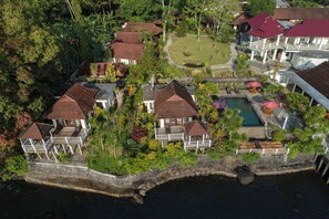 An aerial view of a resort with multiple buildings, a swimming pool, and lush greenery.