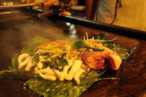 A hot plate with food ingredients, including vegetables and meat, on a wooden surface. - Phi Phi Rimlay Resort (Phi Phi Islands)
