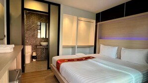 A modern hotel room with a large bed, a small bathroom, and a wooden desk. - Phi Phi Rimlay Resort (Phi Phi Islands)
