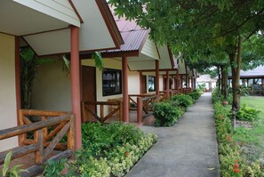 A row of wooden-framed buildings with a covered walkway and lush greenery. - Phi Phi Rimlay Resort (Phi Phi Islands)