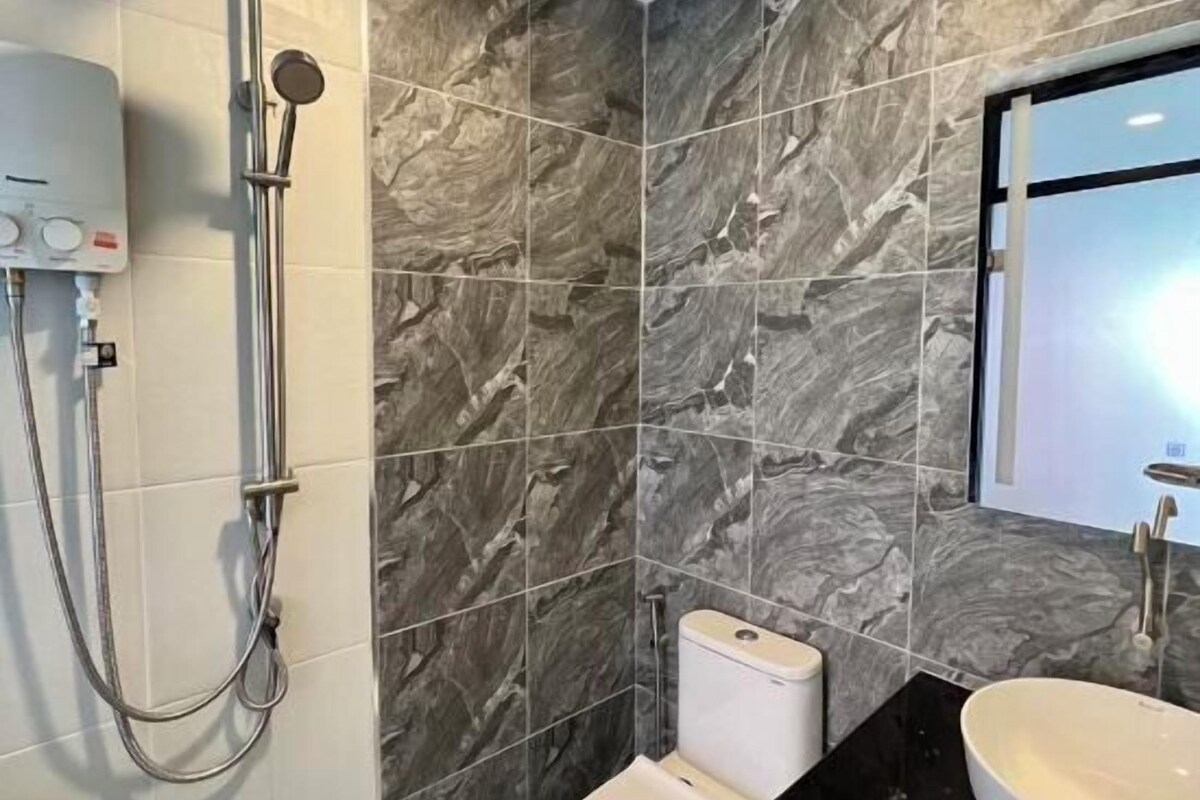 A bathroom with a shower, toilet, and sink, all with marble tile walls.